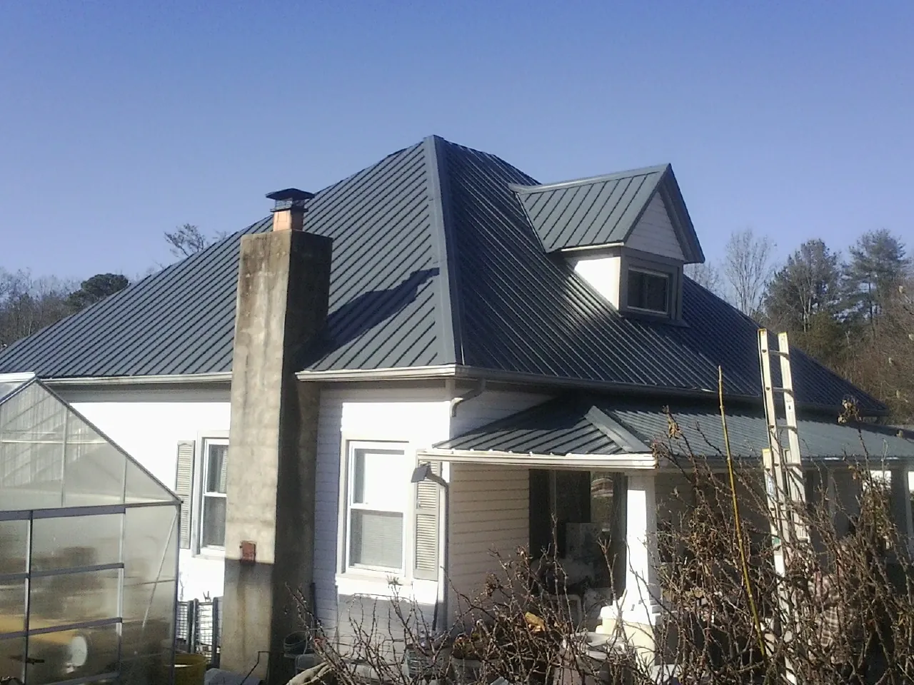 Dark blue standing seam metal roof on a white farmhouse with dormer — Slate & Tile Roof Repair by Roofing Brothers in Kanosh