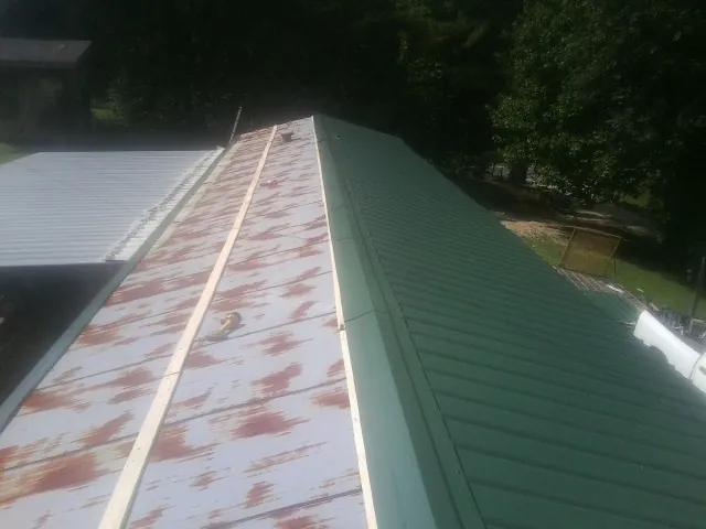 Old rusted panels beside newly installed green metal roofing — Wind Damage Roof Repair by Roofing Brothers in Kanosh