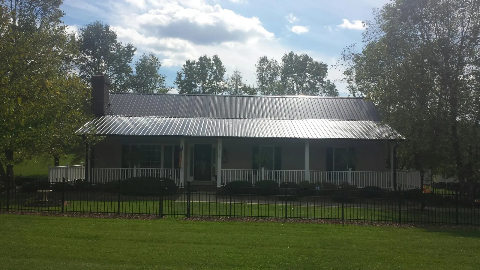 Gray metal roof on a brick ranch with a full width front porch — Gutter Guard Installation work by our crew in Kanosh