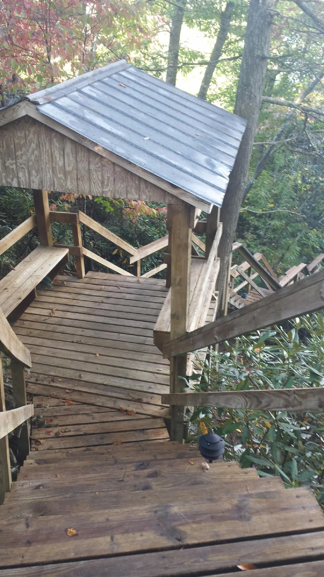 Metal roofed shelter over wooden steps on a wooded walkway — Skylight Repair & Installation work by our crew in Kanosh